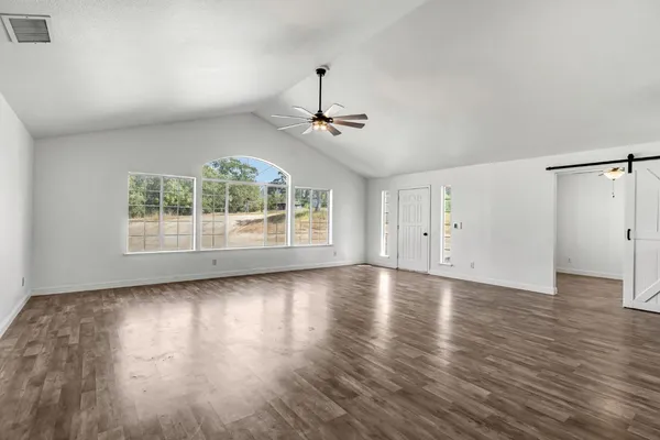 a view of a room with wooden floor ceiling fan and windows
