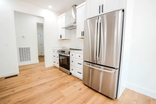 a large white kitchen with a sink a refrigerator and window