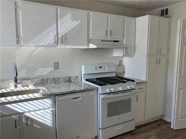 a kitchen with granite countertop stainless steel appliances white cabinets and a sink