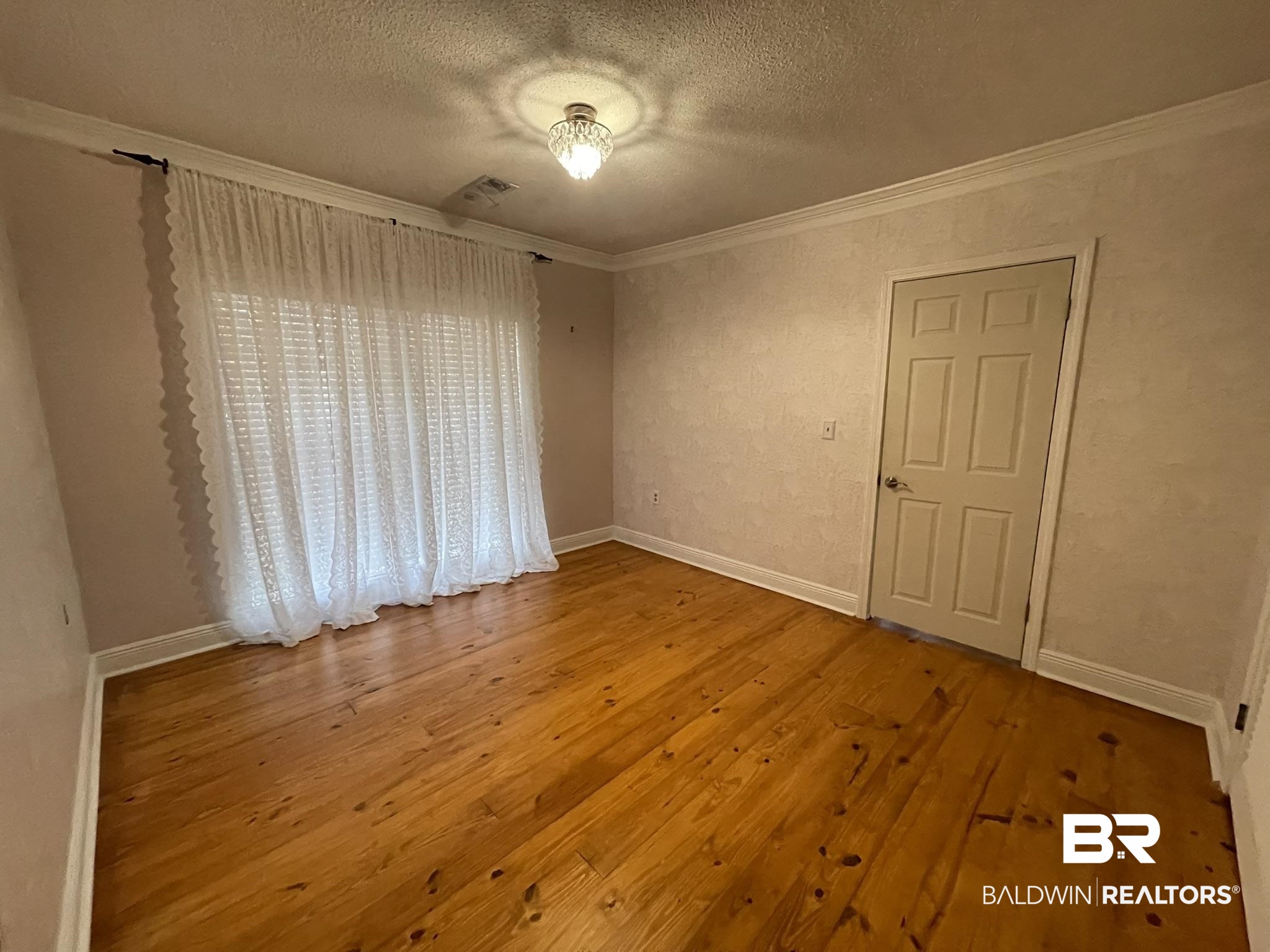 6621 Purvis Road Daphne, AL 36527 - Photo 23 of 59 Empty room with crown molding, light wood-style flooring, and a textured ceiling