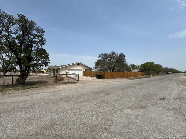 a view of a house with a yard and large trees