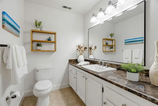 a bathroom with a granite countertop toilet sink and mirror