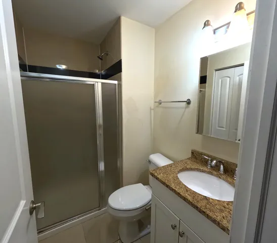 a bathroom with a granite countertop sink toilet and shower