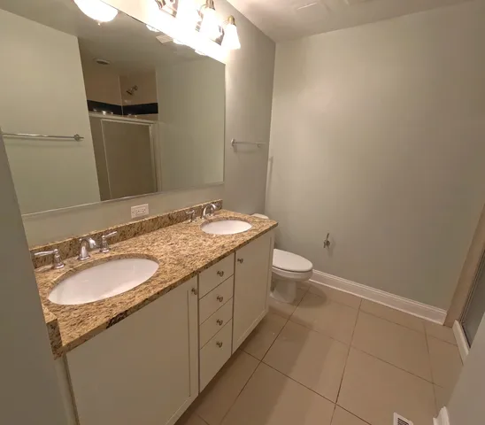 a bathroom with a granite countertop sink toilet and mirror