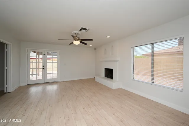 a view of an empty room with a window and wooden floor