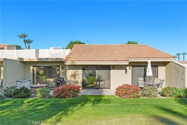 a view of a white house with a big yard and potted plants