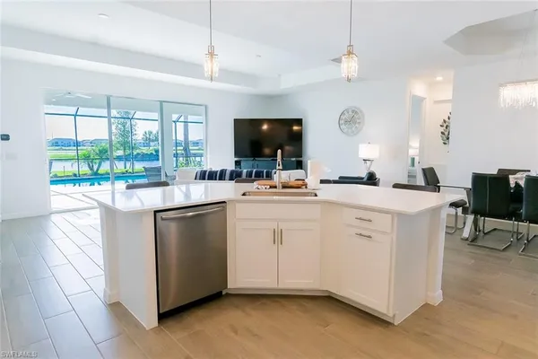 a kitchen with kitchen island a sink and a stove with a living room
