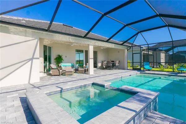 a view of a backyard with swimming pool table and chairs under an umbrella