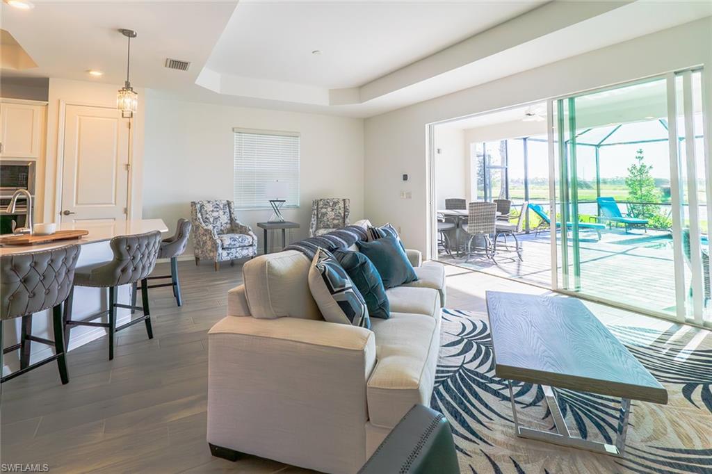 5534 Hampton Links Court Ave Maria, FL 34142 - Photo 7 of 50 a living room with furniture a large window and wooden floor