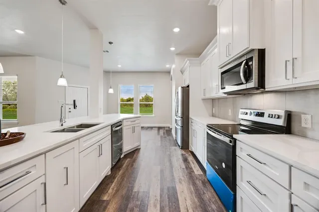 a large kitchen with stainless steel appliances granite countertop a lot of counter space and a sink