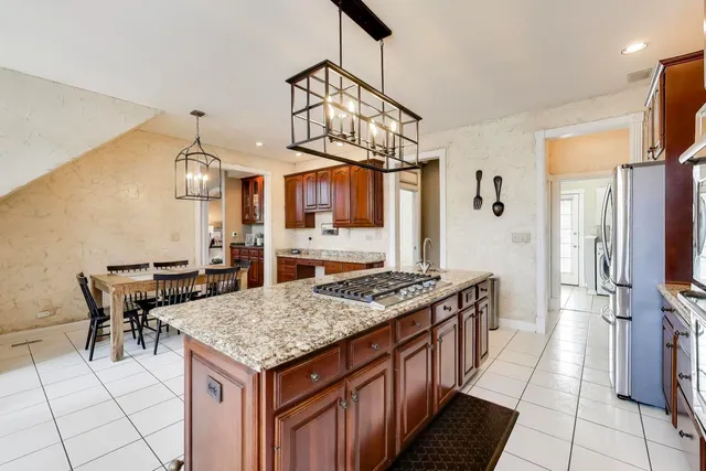 a very nice looking open kitchen with stainless steel appliances granite countertop a sink dishwasher a stove a dining table and chairs with wooden floor