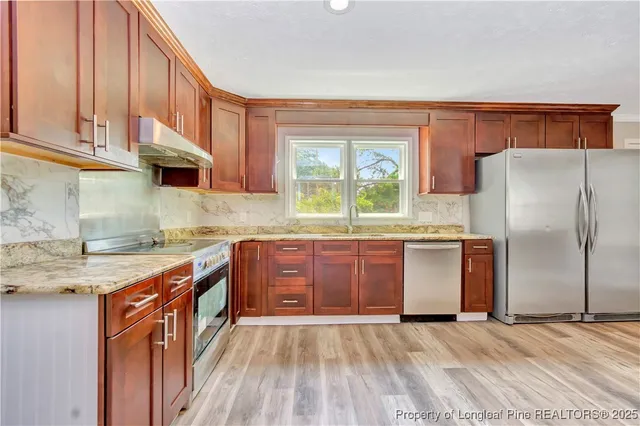 a kitchen with stainless steel appliances granite countertop a refrigerator a sink dishwasher a stove with wooden cabinets and floor