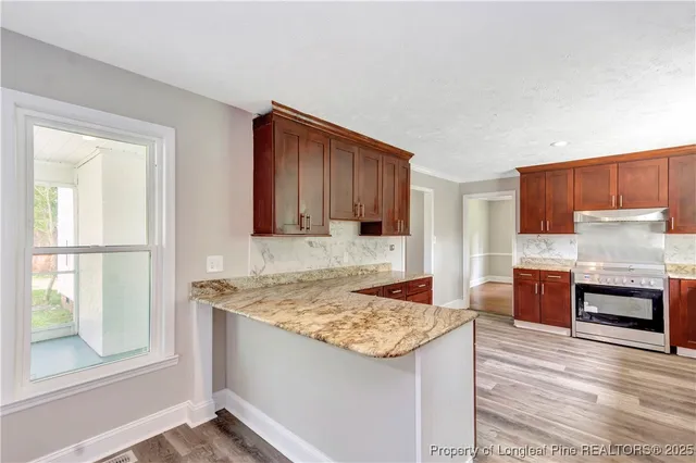 a kitchen with granite countertop wooden cabinets and a stove