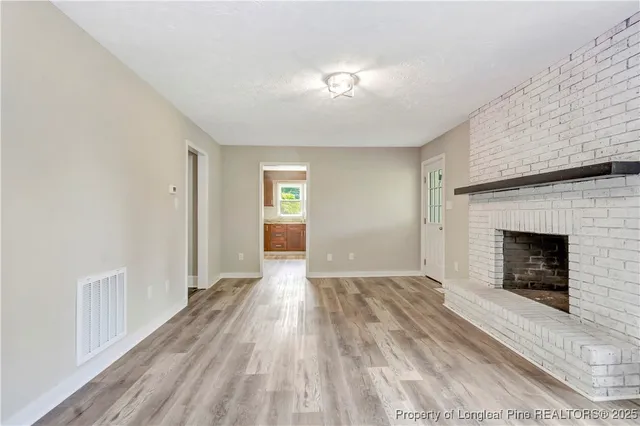 a view of an empty room with window and fire place