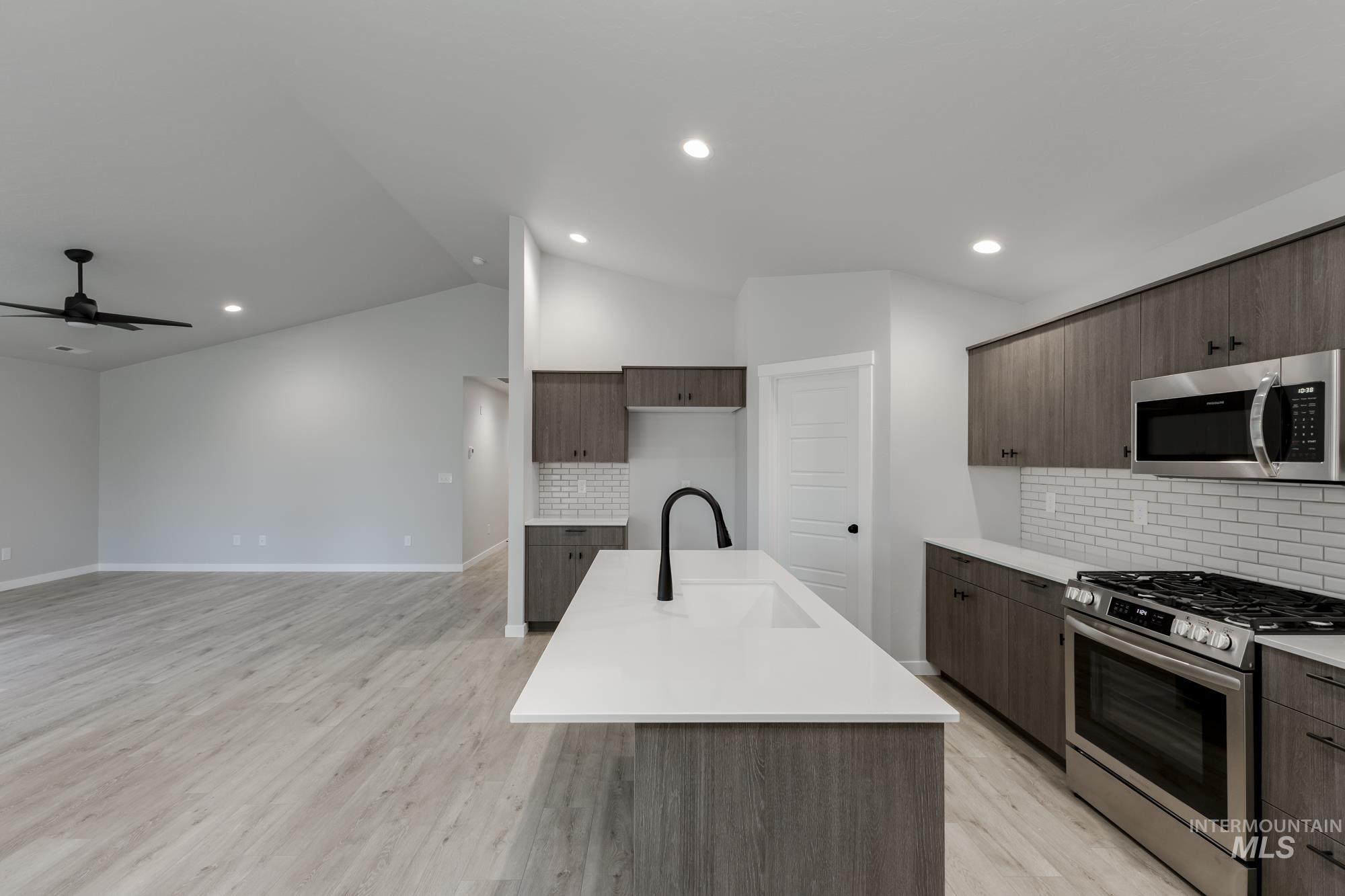 907 North Aleppo Way Meridian, ID 83642 - Photo 5 of 19 Kitchen with stainless steel appliances, tasteful backsplash, a center island with sink, light wood-style flooring, and lofted ceiling