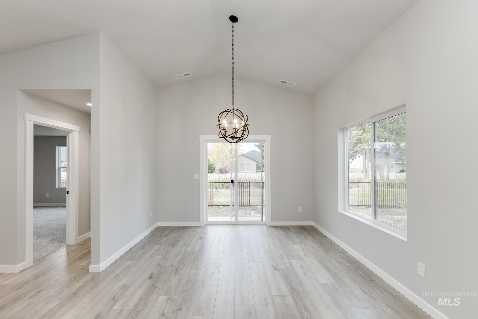 907 North Aleppo Way Meridian, ID 83642 - Photo 6 of 19 Unfurnished dining area featuring lofted ceiling, healthy amount of natural light, light wood-type flooring, and a chandelier