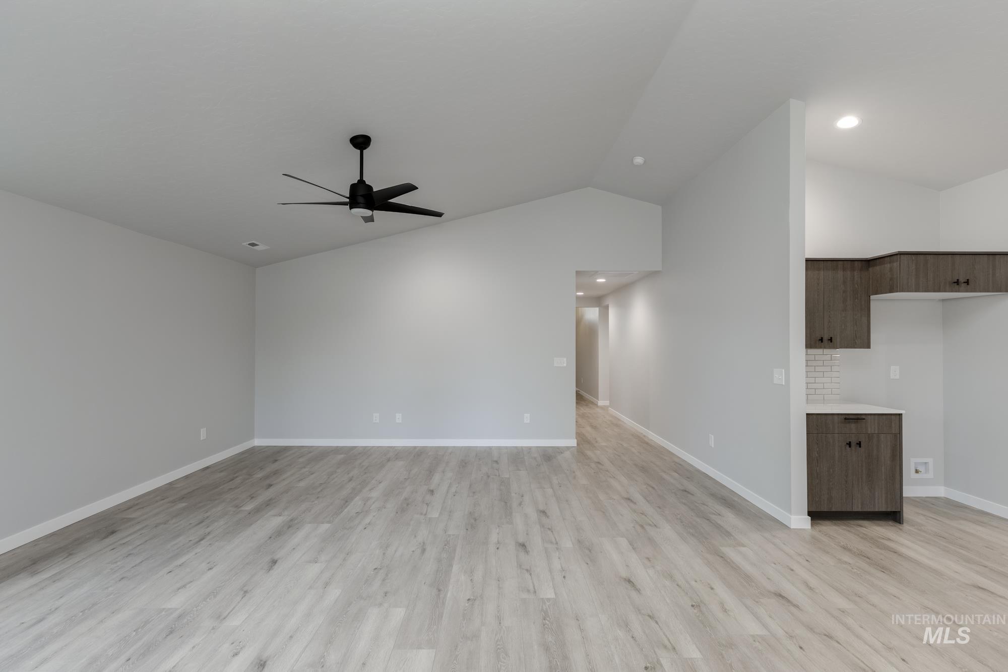 907 North Aleppo Way Meridian, ID 83642 - Photo 8 of 19 Unfurnished living room with lofted ceiling, light wood-style flooring, and a ceiling fan