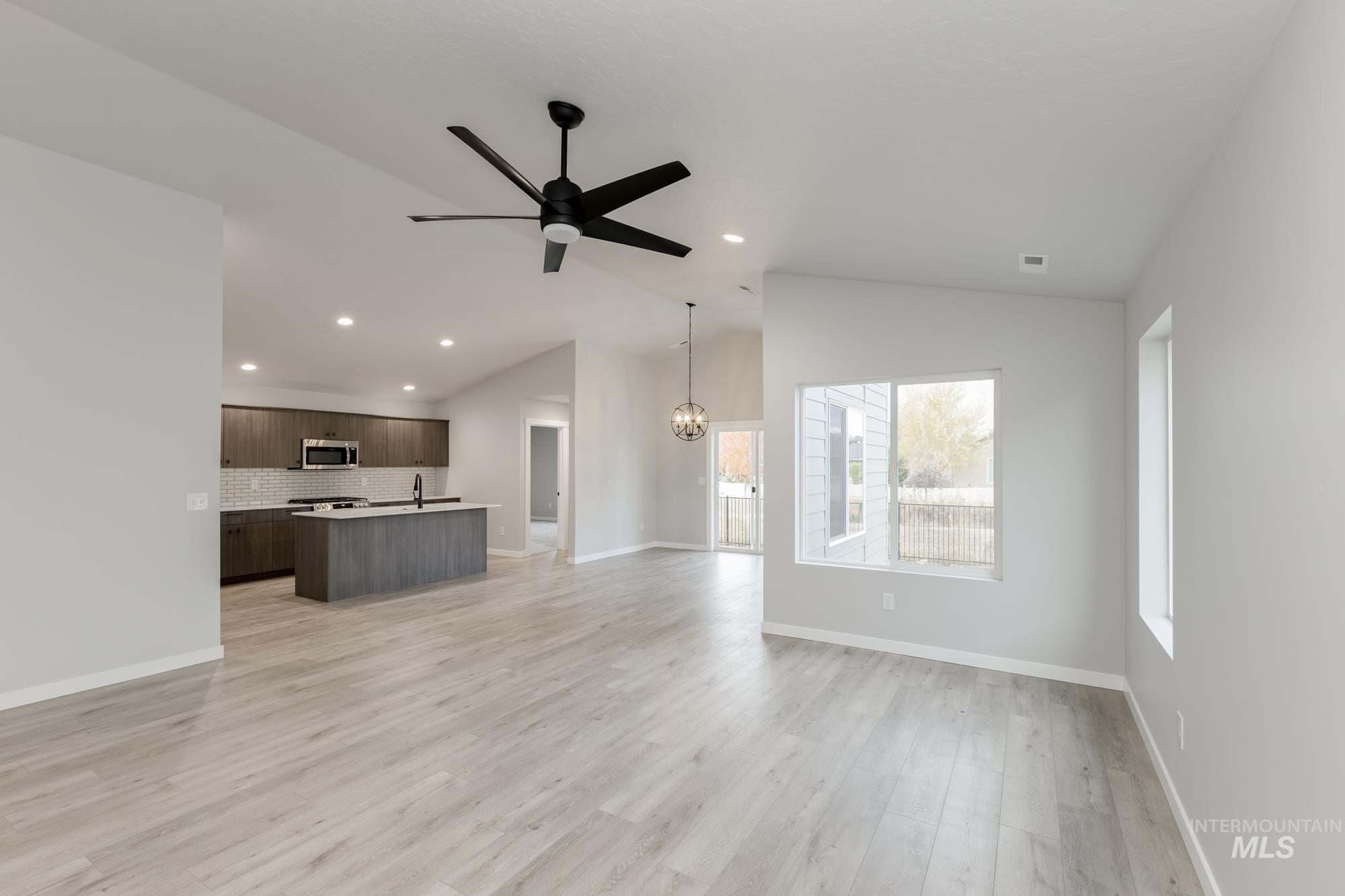 907 North Aleppo Way Meridian, ID 83642 - Photo 9 of 19 Unfurnished living room featuring ceiling fan, light wood finished floors, lofted ceiling, recessed lighting, and a chandelier