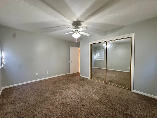 an empty room with closet and a ceiling fan