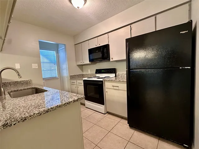 a kitchen with granite countertop a refrigerator stove and sink