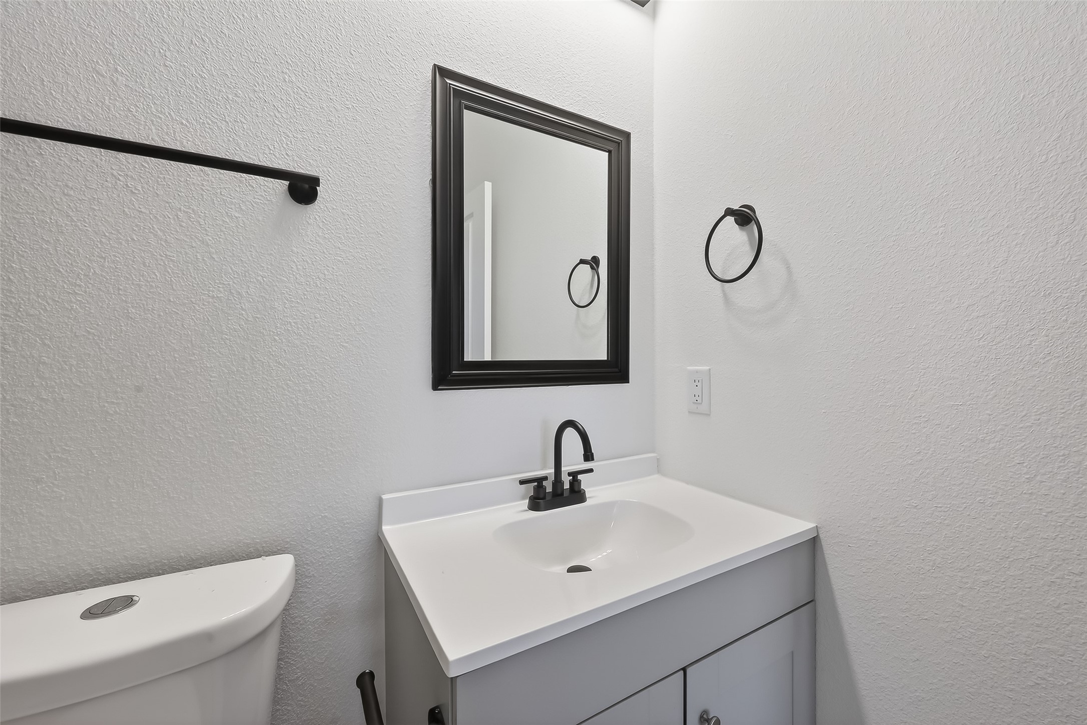 3514 Good Hope Street, Unit B Houston, TX 77021 - Photo 19 of 26 This bathroom features a modern design with a sleek white vanity, black fixtures, and a wall-mounted mirror framed in black. It has a simple, clean aesthetic perfect for contemporary tastes.