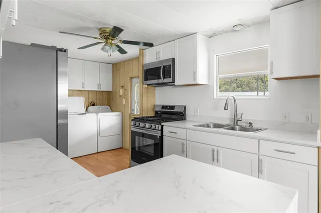 a kitchen with stainless steel appliances granite countertop a sink a stove a refrigerator with grey cabinets