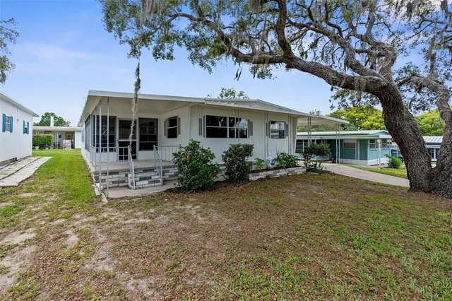 a view of a yard in front of a house with large tree