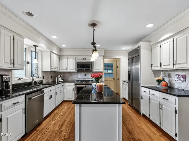 a kitchen with white cabinets stainless steel appliances and a counter space