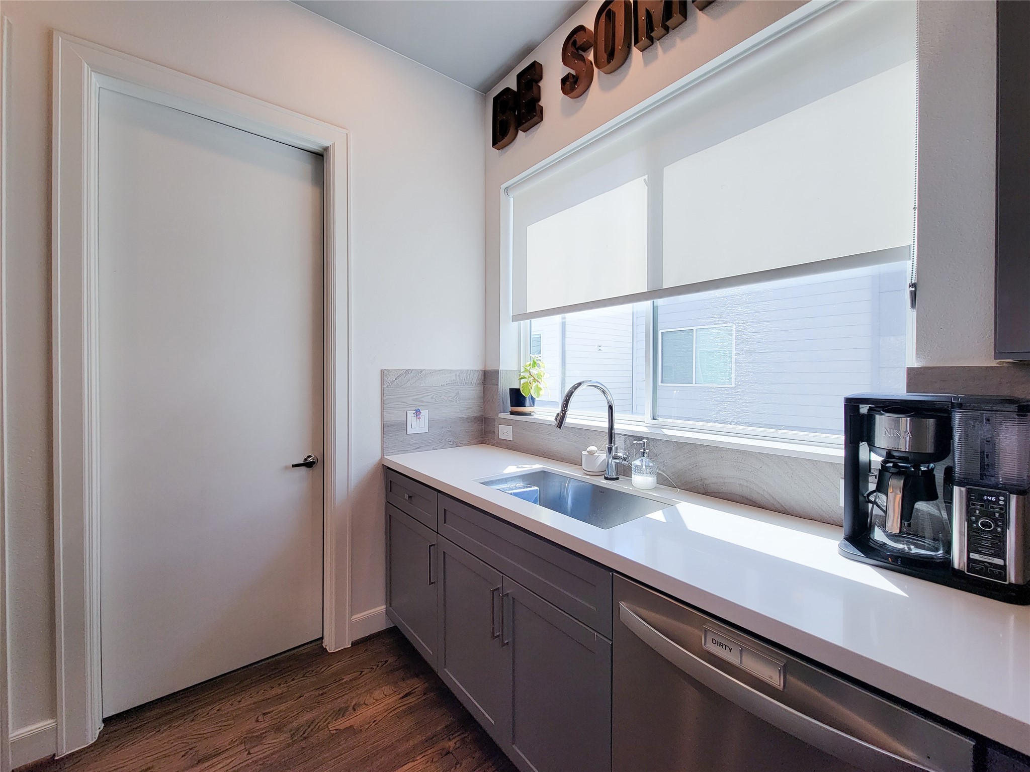 1705 Eado Point Lane Houston, TX 77003 - Photo 28 of 50 Bright and modern kitchen with sleek cabinetry, hardwood floors, and a large window providing natural light. Features a stainless steel sink and built-in dishwasher with clean lines and a minimalist design.