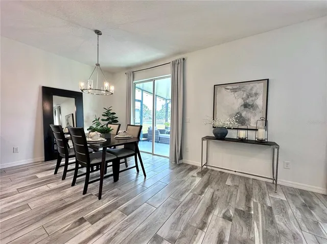 a living room with stainless steel appliances furniture wooden floor and a view of kitchen