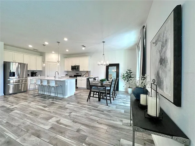 a view of a dining room with furniture a kitchen and chandelier