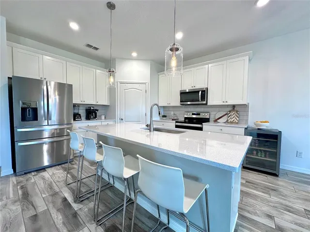 a large kitchen with stainless steel appliances a sink dishwasher stove refrigerator and cabinets