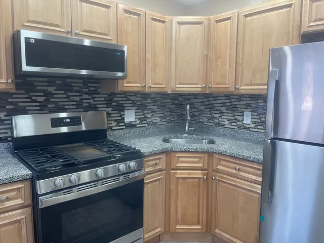 a kitchen with granite countertop a refrigerator sink and cabinets