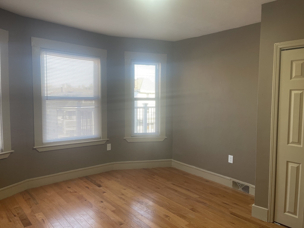 1002 River Street, Unit 3 Boston, MA 02136 - Photo 8 of 11 an empty room with wooden floor and windows