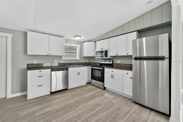 a kitchen with granite countertop white cabinets and white appliances