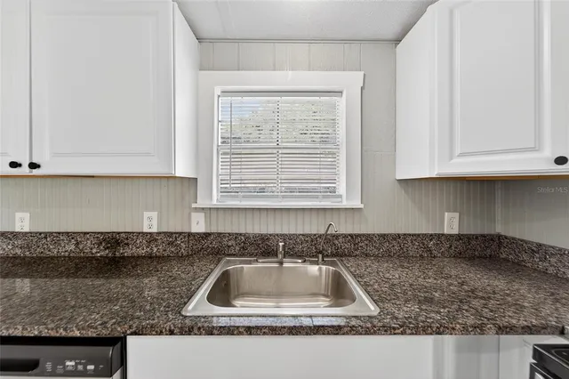 a kitchen with granite countertop white cabinets sink and granite