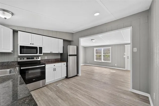 a kitchen with stainless steel appliances granite countertop a stove top oven a sink dishwasher and a refrigerator with wooden floor