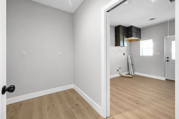 a view of an empty room with wooden floor and a window