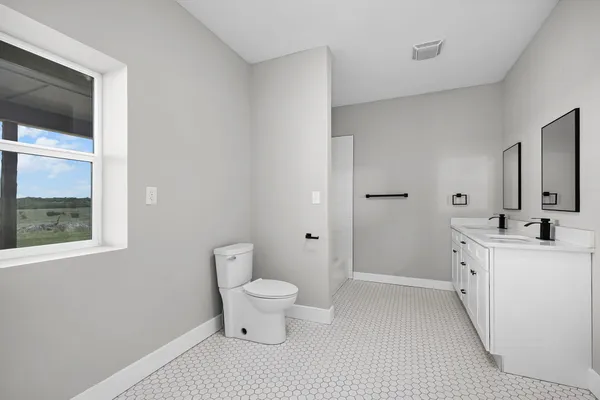 a spacious bathroom with a toilet a sink a mirror and a shower