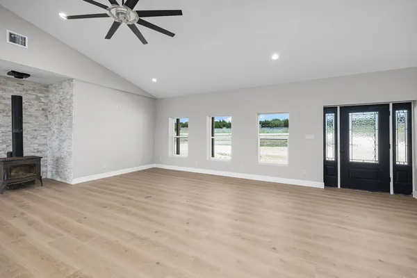 a view of an empty room with a window and wooden floor