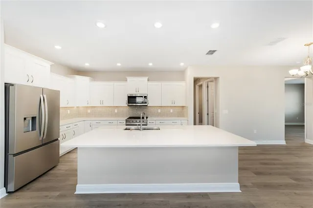 a large kitchen with stainless steel appliances kitchen island a stove a refrigerator a oven and a sink