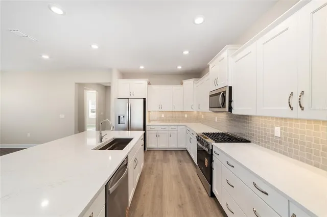 a large kitchen with cabinets a sink dishwasher a stove and refrigerator with wooden floor