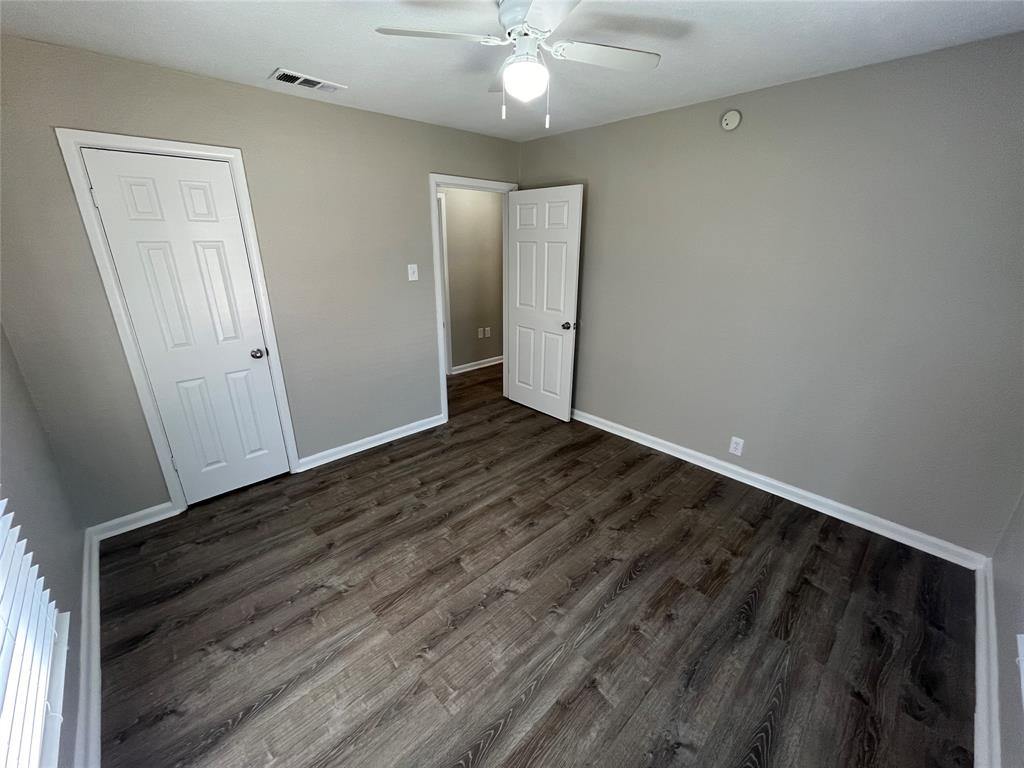 1622 Centerville Road Dallas, TX 75228 - Photo 16 of 19 Wood-finish flooring, neutral gray wall tones, white trim, paneled doors, and a ceiling fan with integrated lighting