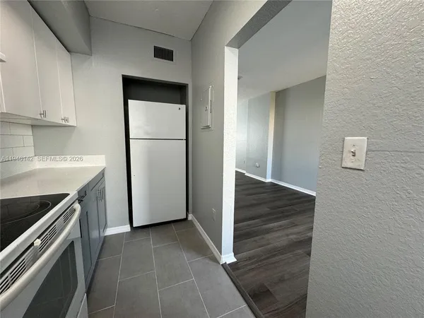a kitchen with a refrigerator sink and cabinets