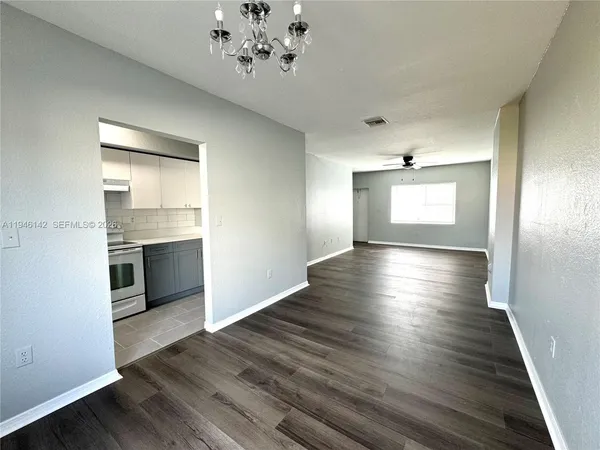 a view of an empty room with a window and wooden floor