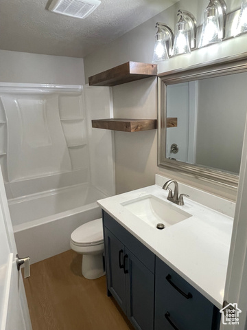 658 West 500 South Logan, UT 84321 - Photo 24 of 25 Full bathroom featuring a textured ceiling, dark wood-type flooring, vanity, and shower / tub combination