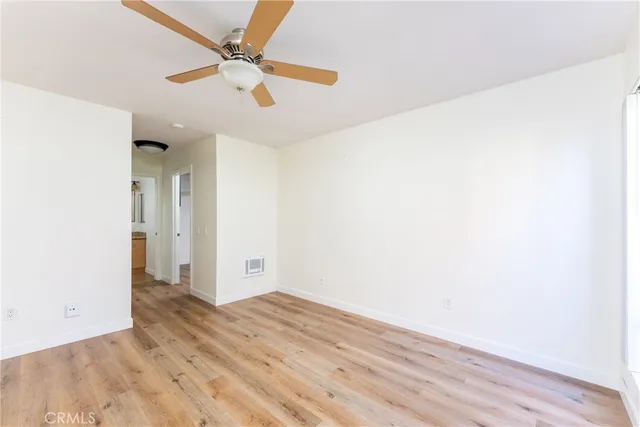 an empty room with wooden floor and ceiling fan