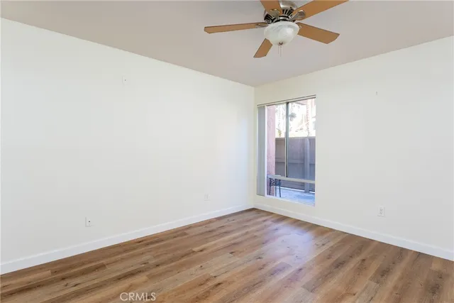 an empty room with wooden floor fan and windows