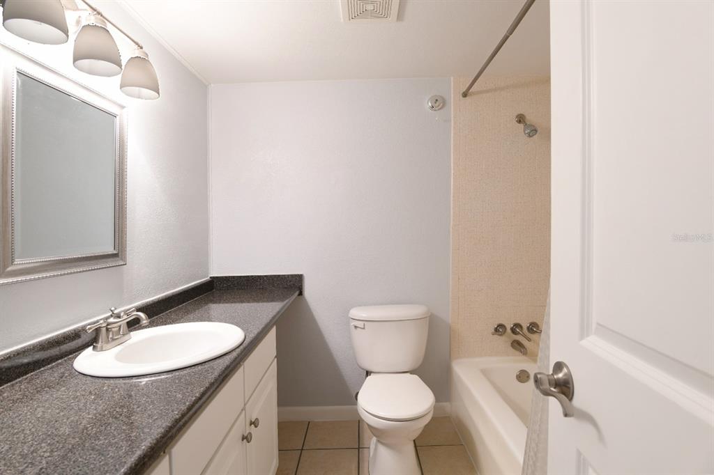 507 Northwest 39th Road, Unit 215 Gainesville, FL 32607 - Photo 13 of 21 a bathroom with a granite countertop sink toilet a mirror and shower