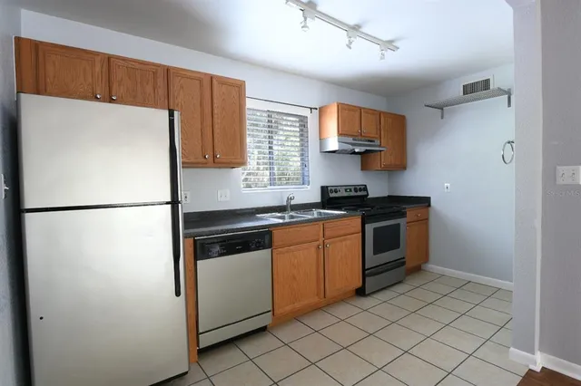 a kitchen with stainless steel appliances granite countertop a refrigerator a sink and a stove